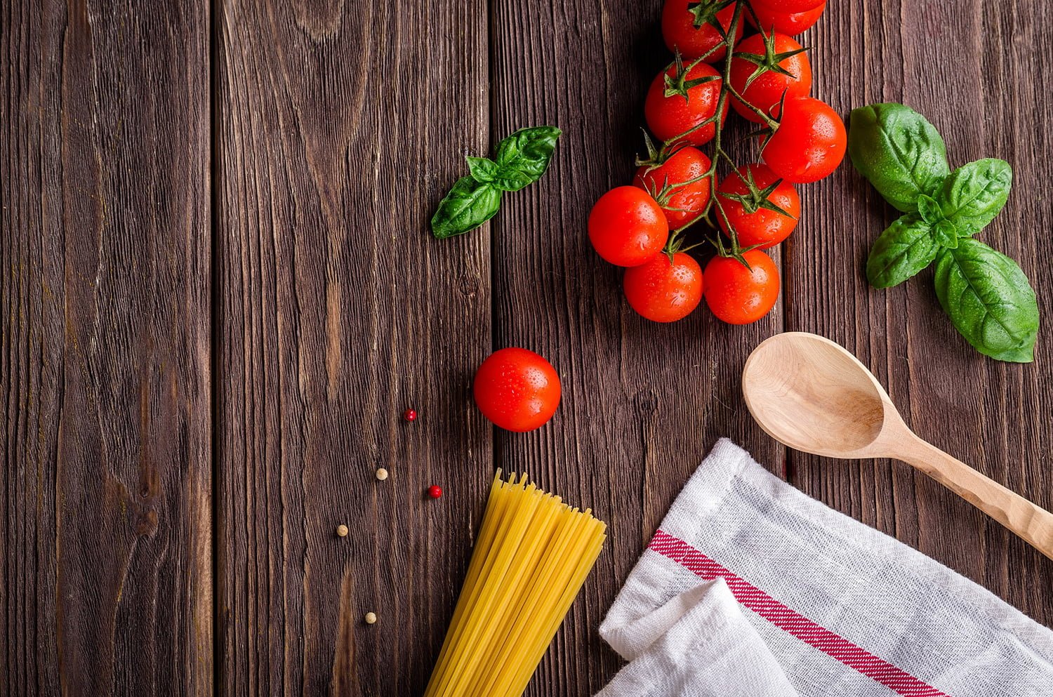 Wooden table with pasta, basil and tomatoes